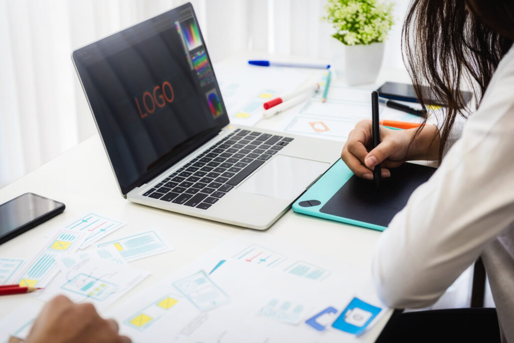 A designer sketching a custom logo design on a tablet or notebook