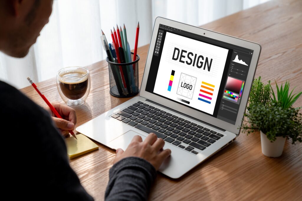 Graphic designer working on a laptop, creating a logo design with color palettes.