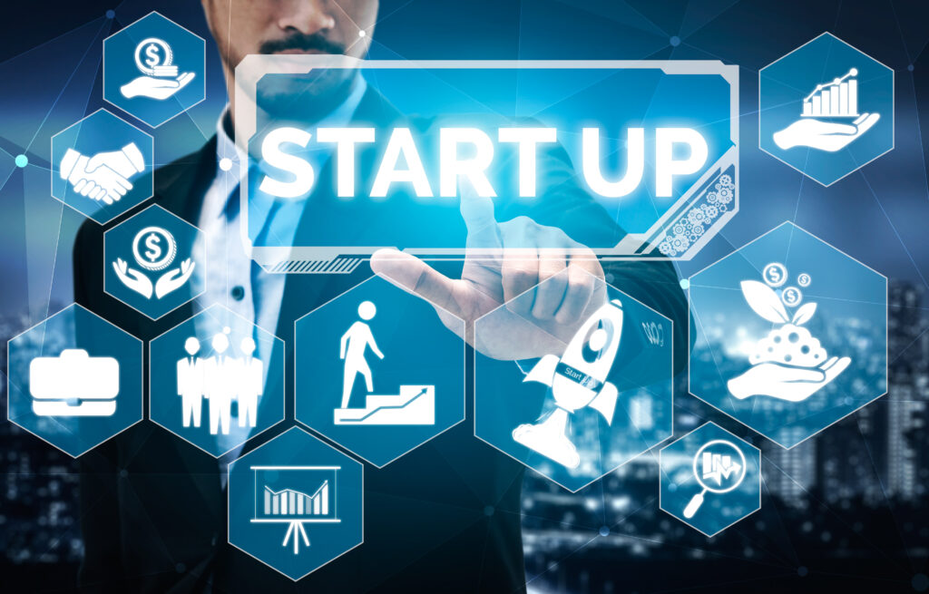 Businessman touching virtual "START UP" icon with business growth and finance symbols.